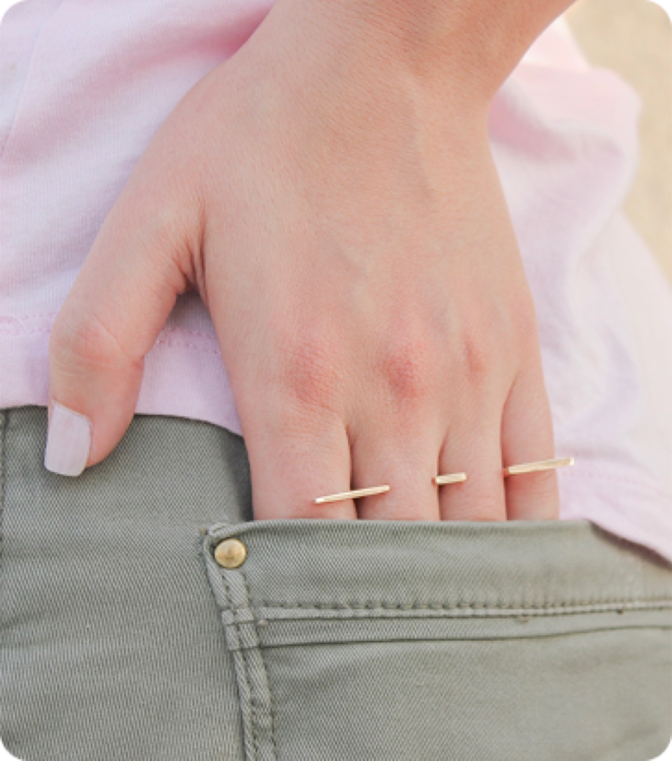 A hand at the hip, gold line rings across the fingers